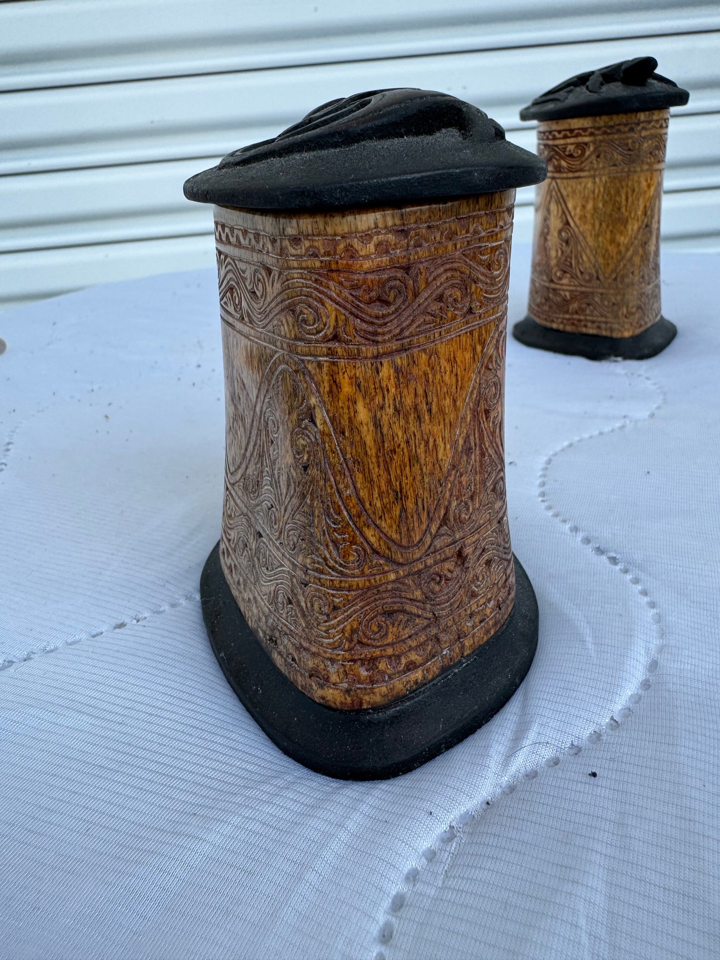Side view of antique bone storage box with intricate carvings and black lid