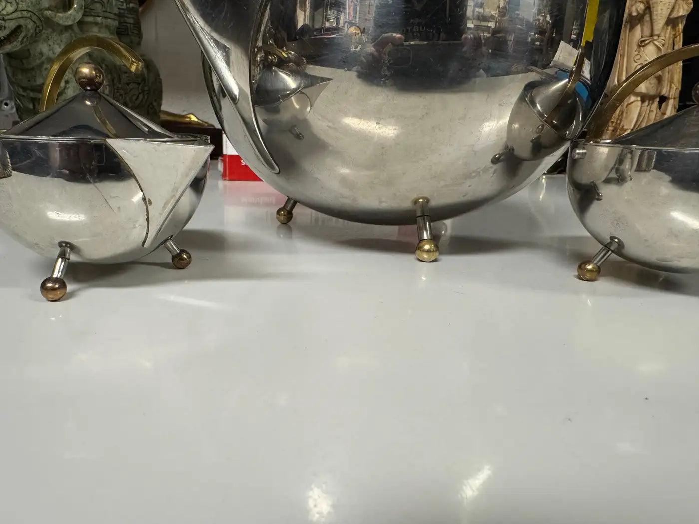 Modernist stainless steel creamer with brass handle arch and ball foot from Carsten Jorgensen tea set