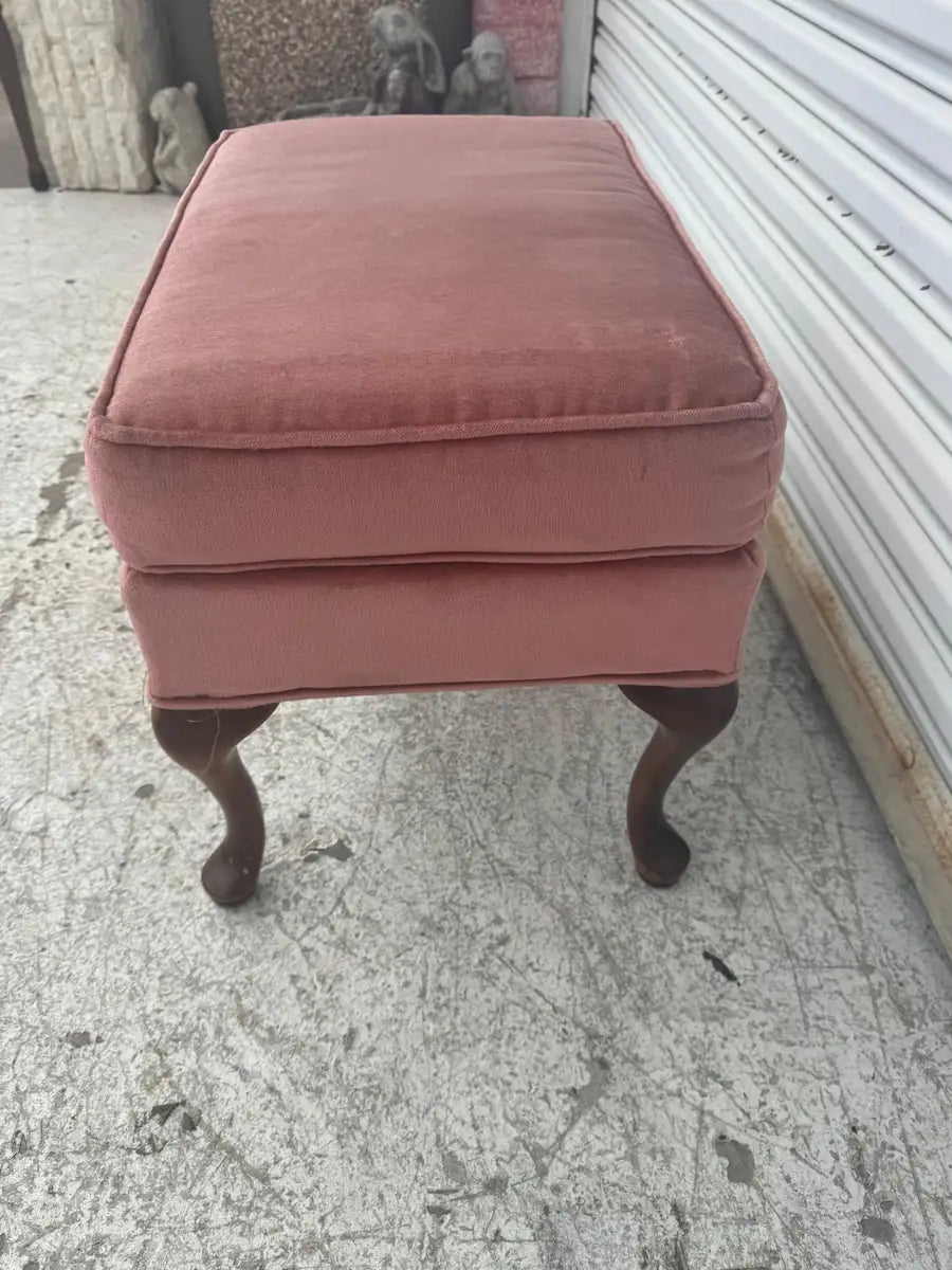 Antique ottoman with plush cushioned top and curved legs