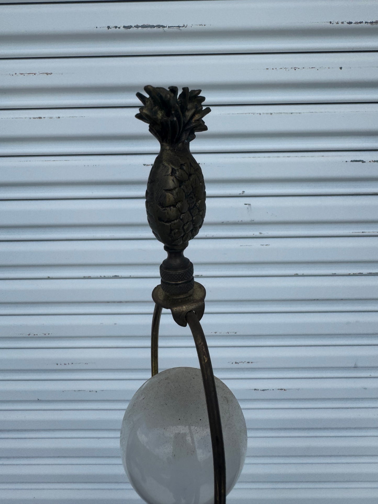 Regency-style gold pineapple table lamp plugged in on polished wood furniture