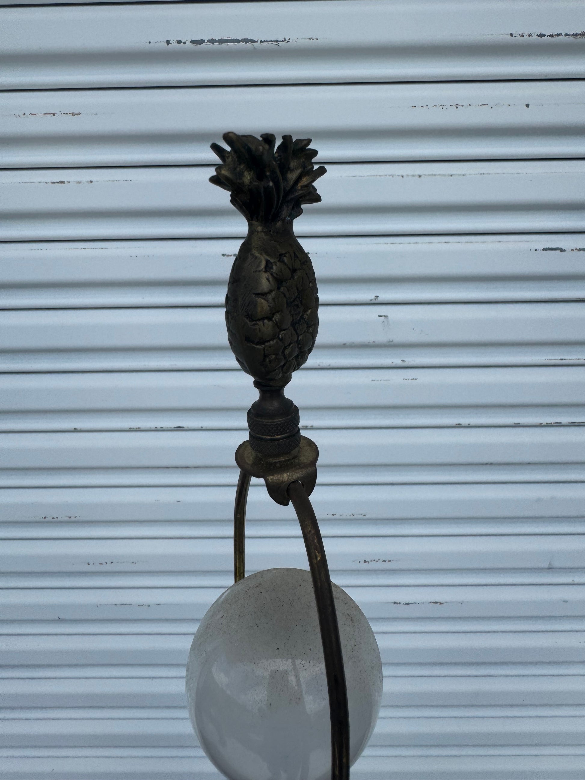 Regency-style gold pineapple table lamp plugged in on polished wood furniture