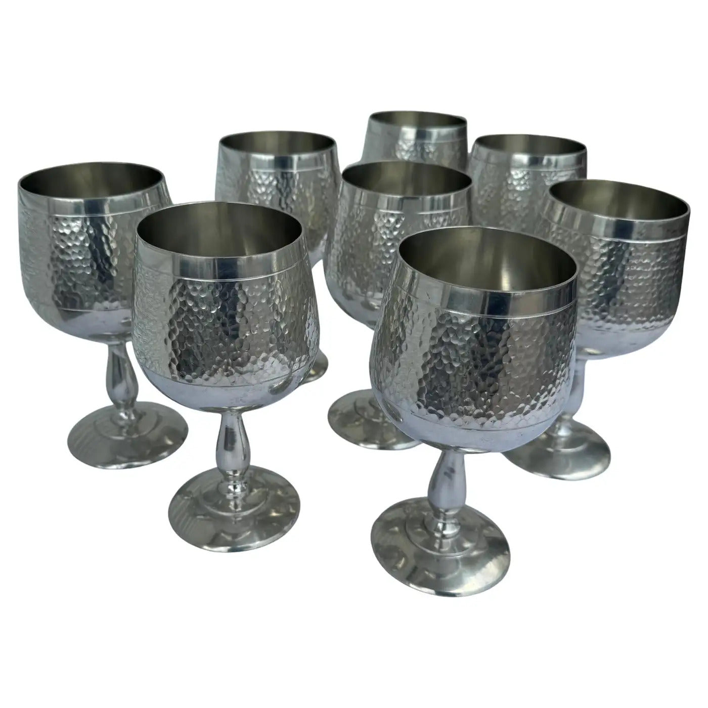 Close-up of vintage hammered pattern metal goblets with reflective silver shine.