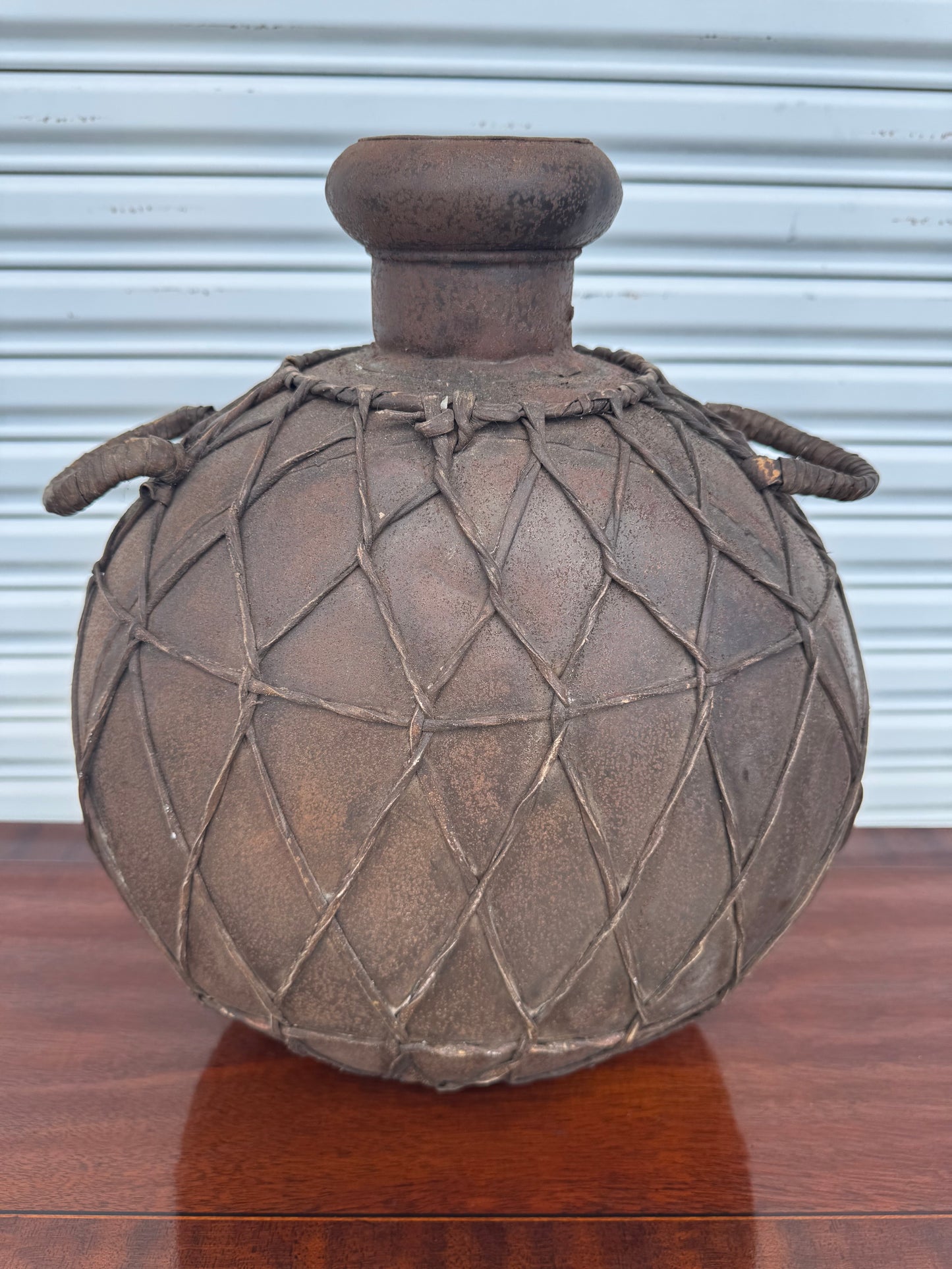Vintage composite cast jug with decorative rope net and rustic double handles.