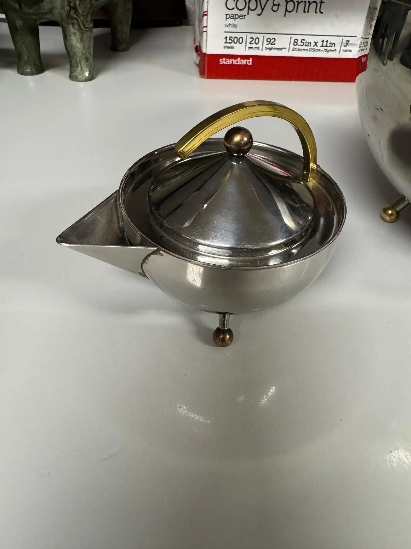 Design-focused stainless steel tea set with ball feet and conical lids ideal for modern kitchen and serving décor.