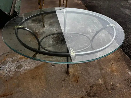Oval glass coffee table with steel frame and brass accents