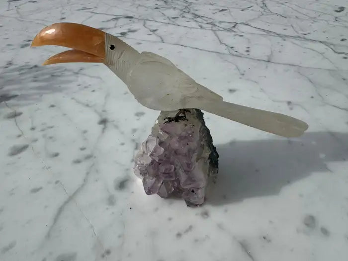 Crystal parrot carving perched on purple amethyst