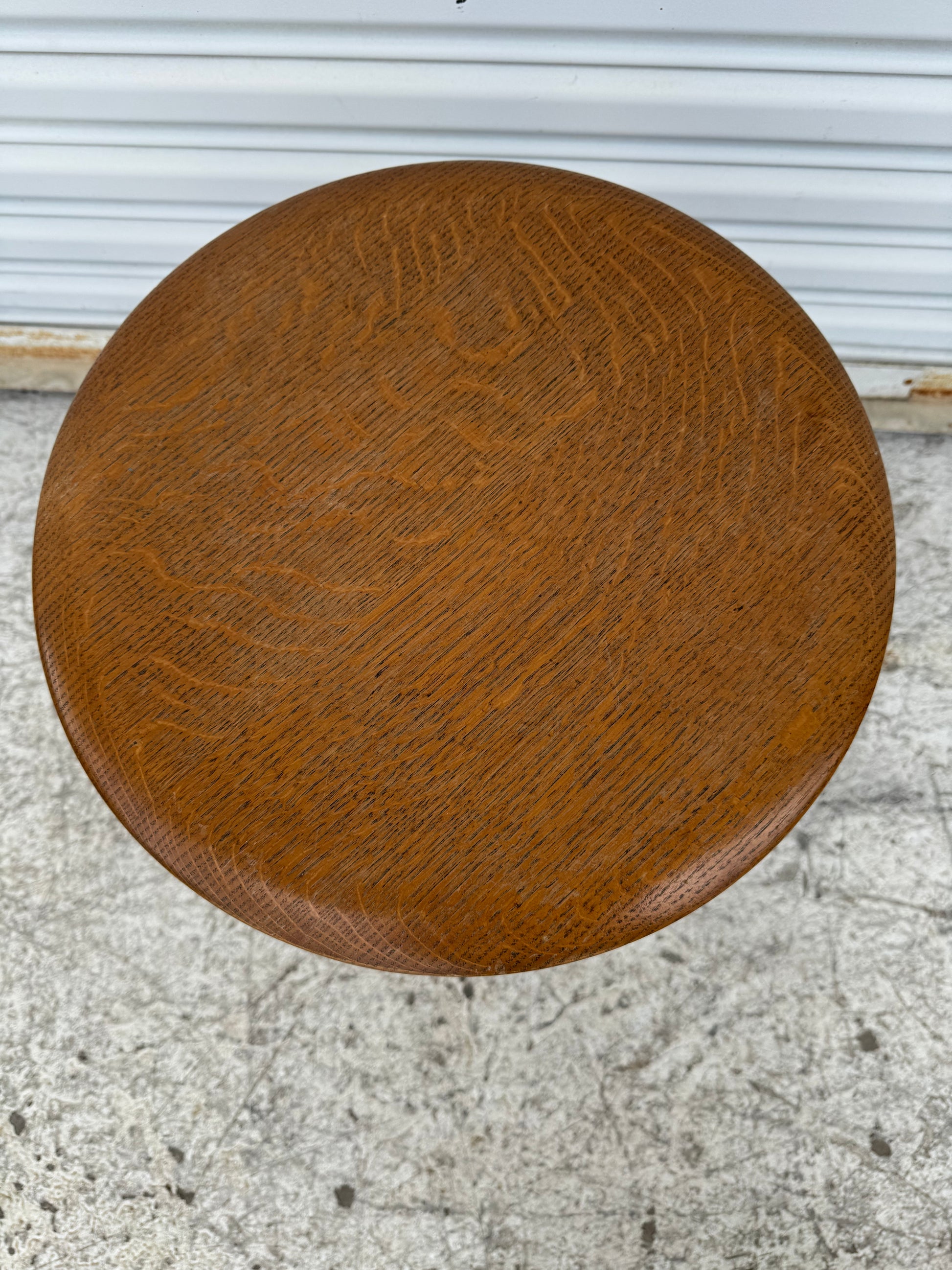 Overhead view of round oak seat on antique piano stool, showing intricate wood grain