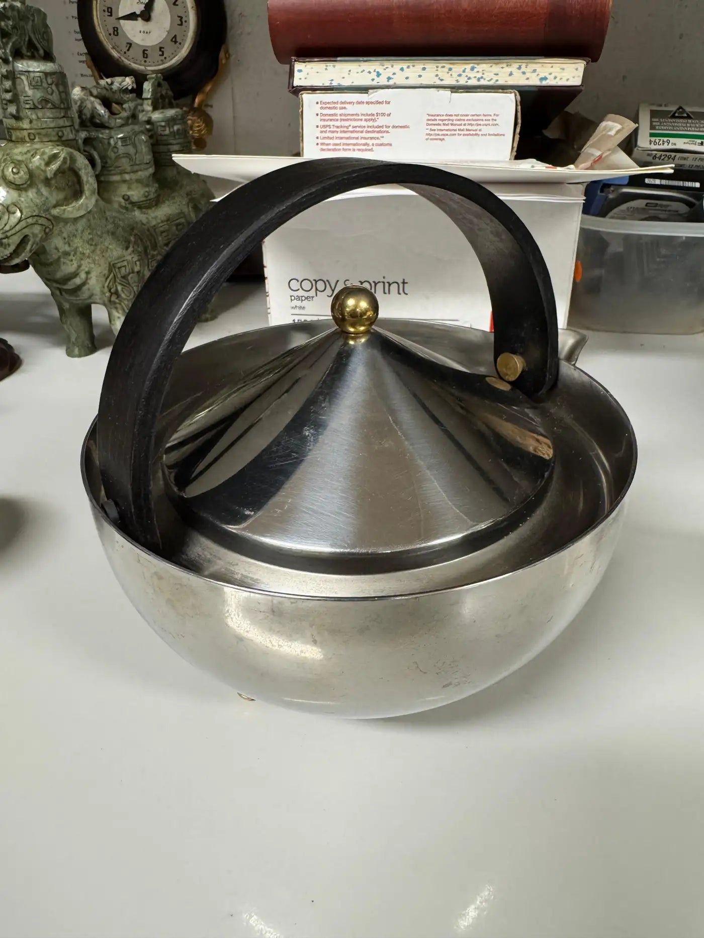 Three piece Bodum stainless steel and brass ball tea service including teapot, creamer, and sugar bowl on studio background.