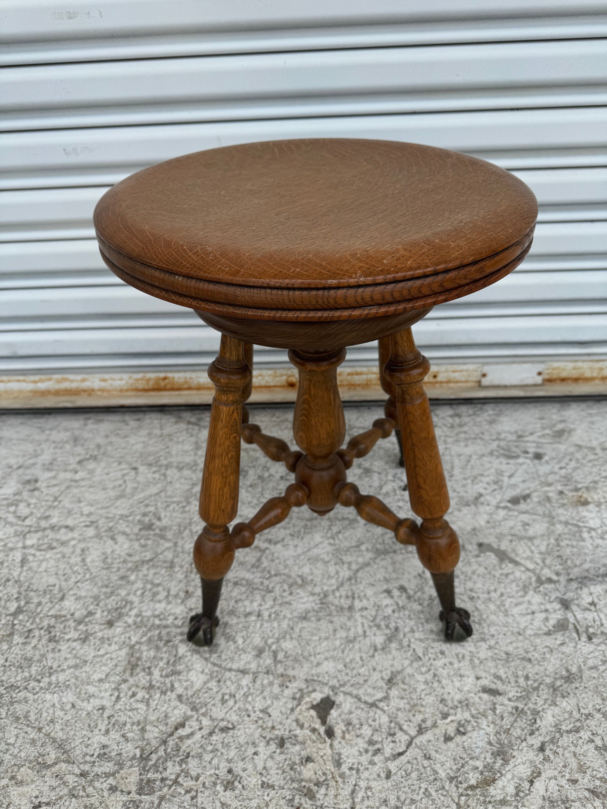 Close-up of Victorian-style piano stool featuring turned wooden legs and iron claw feet.