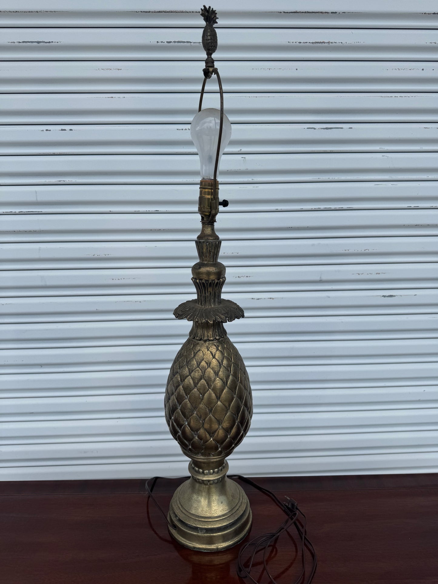 35-inch Regency pineapple table lamp with antique brass finish on wooden surface