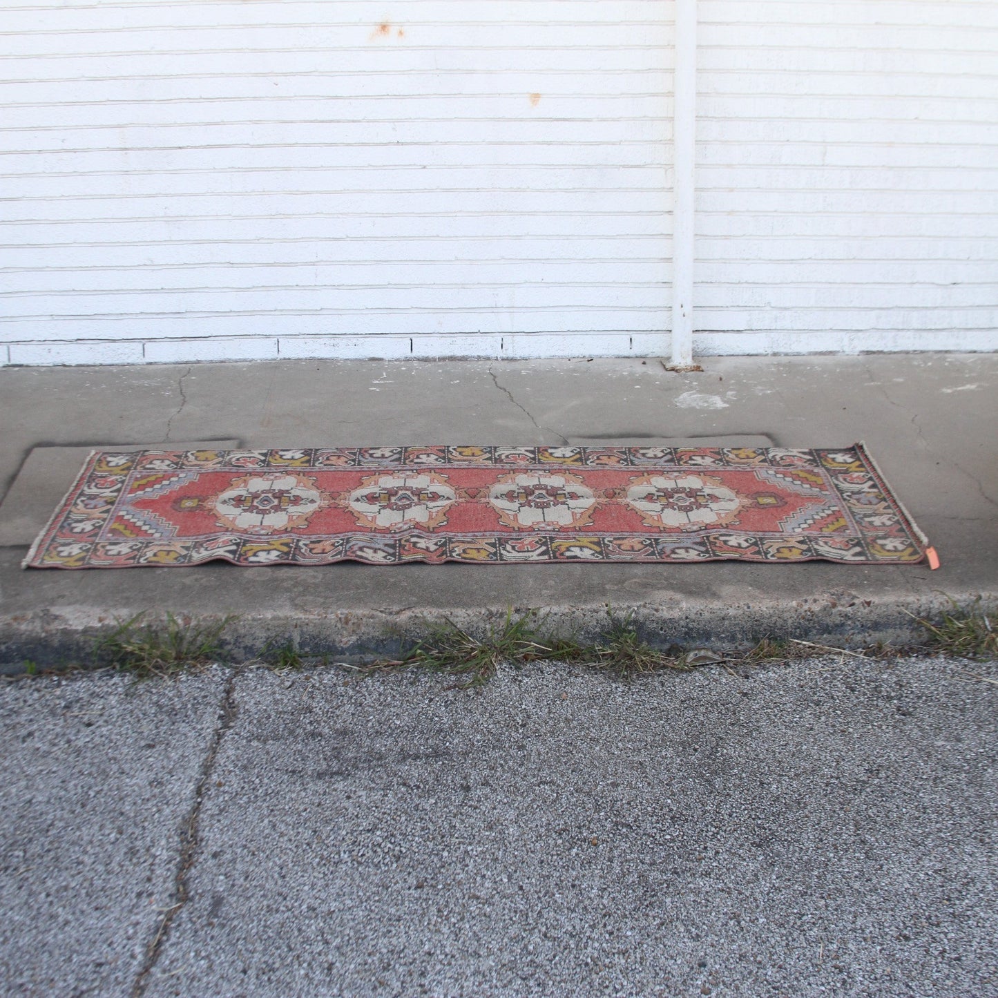 Vintage pink Turkish runner rug with floral patterns on cement
