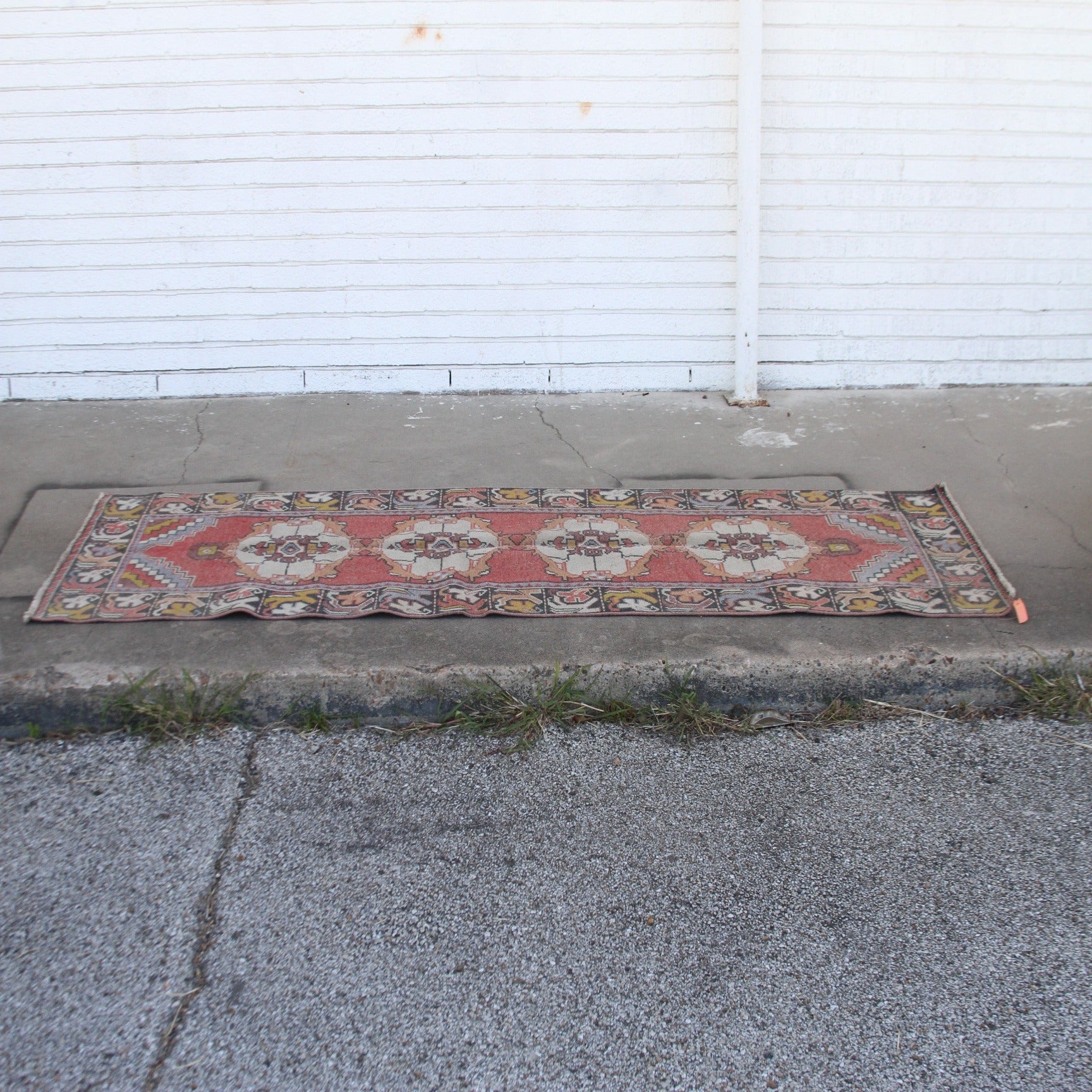 Vintage pink Turkish runner rug with floral patterns on cement