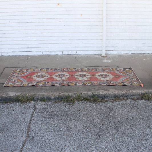 Vintage pink Turkish runner rug with floral patterns on cement